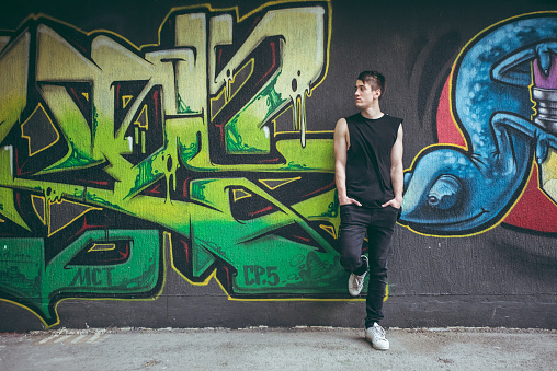 Young caucasian handsome man leaning on graffiti wall.