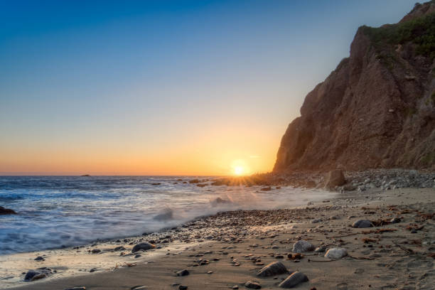 Tall Cliffs of Dana Point At Sunset Beautiful coastal view of beach as waves wash onto the shore, tall cliffs in the background, and the sun on the horizon at dusk, Dana Point, California dana point stock pictures, royalty-free photos & images