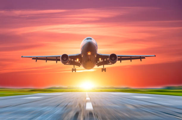 istock Airplane landing on the runway behind a bright sunset with a pink sky 1134065970