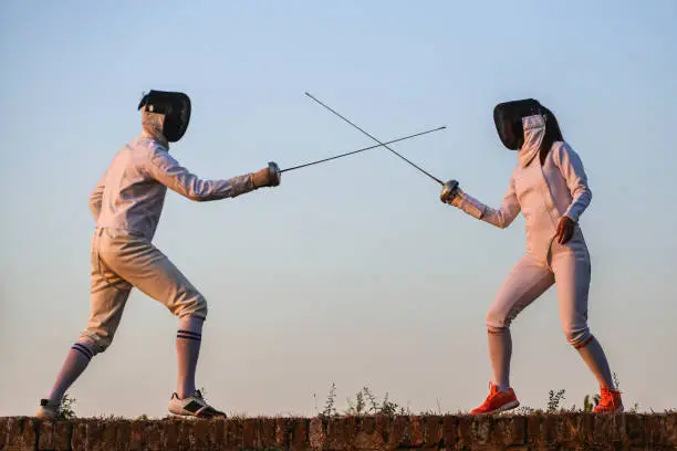 Young man and woman fencing.