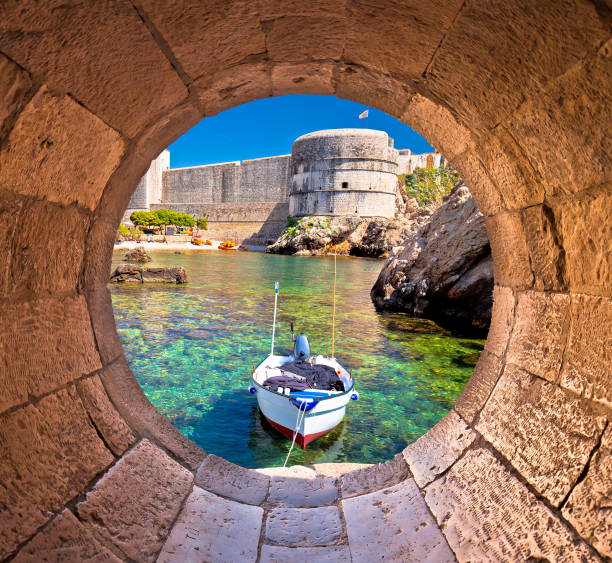 Dubrovnik small harbor under city walls view through stone carved window Dubrovnik small harbor under city walls view through stone carved window, famous tourist destination of Dalmatia dubrovnik walls stock pictures, royalty-free photos & images