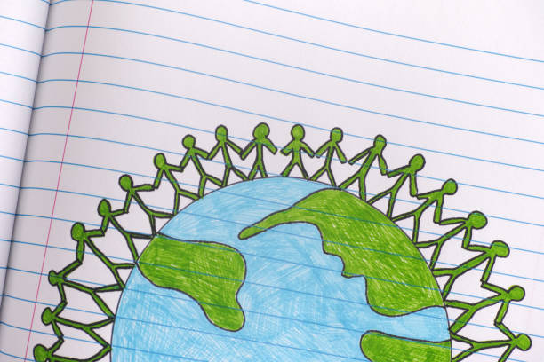 istock Group of people around the world holding hands on lined paper notebook sheet 1134068879