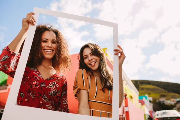 istock Friends holding picture frame outdoors 1134069121