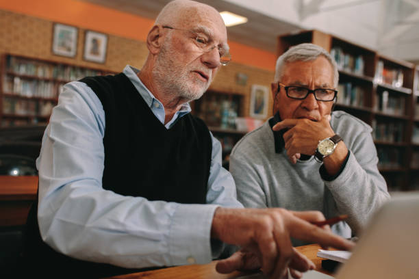 istock Senior men discussing subject sitting in a library 1134070924
