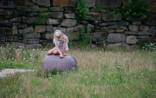 Girl is sitting on a big stone