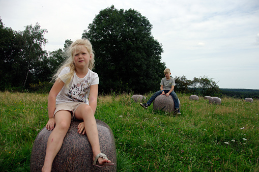Brother and sister  sitting on a big stone