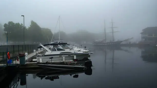 Powerboats and tallship  docked in the early morning fog