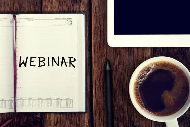 Photo of Webinar. Reminder in the calendar. Coffee with calendar and pencil on a wooden countertop. Reminder about training.