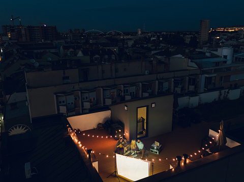 Group of friends having a movie night on the rooftop. Aerial shot. High angle.