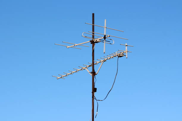 istock Two TV antennas mounted on tall rusted metal pole connected with electrical wires 1134078261