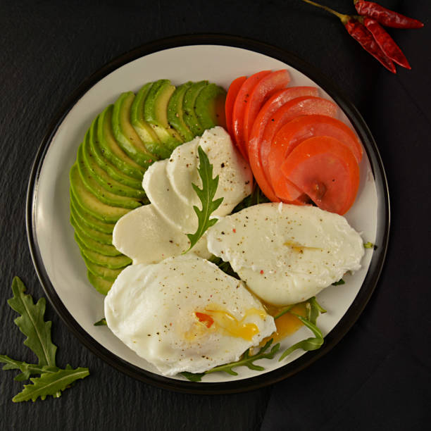 istock Avocado poached eggs. Healthy breakfast food and tomato on black background. 1134079774