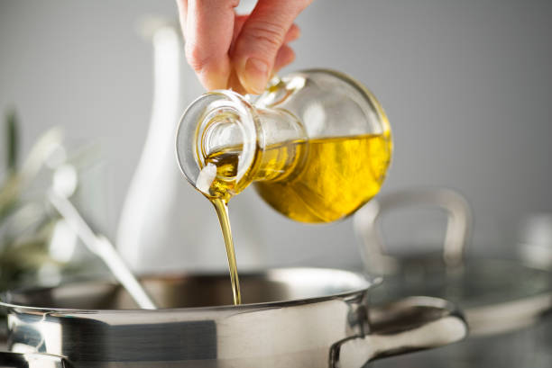 Cooking meal in a pot with olive oil Cooking meal in a pot. Bottle of Extra virgin oil pouring in to pot for cooking meal. Healthy food concept. cooking oil photos stock pictures, royalty-free photos & images