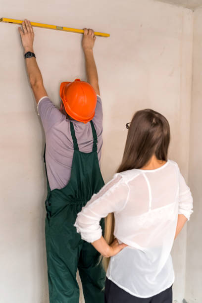 istock Woman controlling how man measuring wall with level tool 1134082638