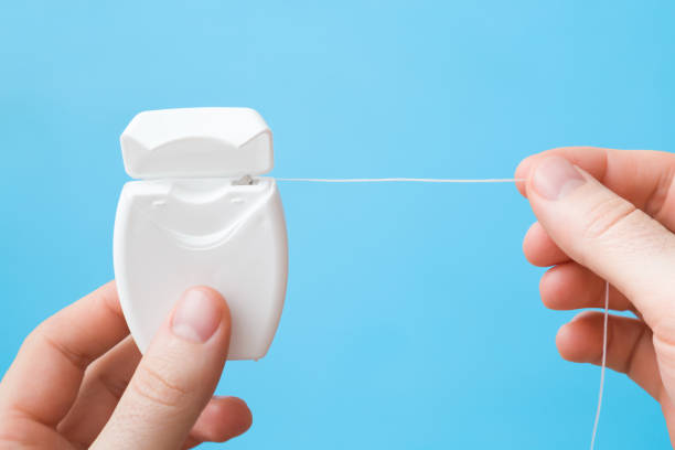 Man fingers holding new white plastic container with dental floss on pastel blue background. Teeth hygiene concept. Closeup. Point of view shot. Man fingers holding new white plastic container with dental floss on pastel blue background. Teeth hygiene concept. Closeup. Point of view shot. dental floss stock pictures, royalty-free photos & images