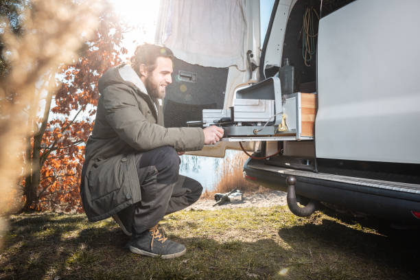 istock Man in front of a van using a build in camping stove 1134084261
