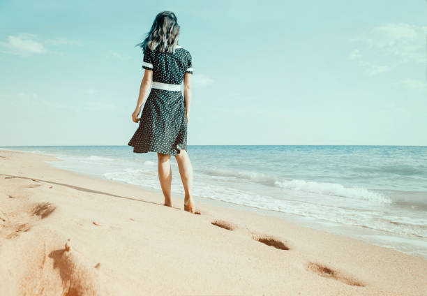 istock Barefoot woman walking on sand beach leaving footprints. 1134085489