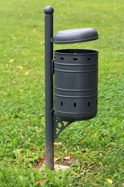 istock New dark grey public metal trash can mounted on concrete foundation surrounded with green grass in local park 1134091115