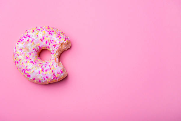 istock Bitten donut with sprinkles on a pink tabletop 1134091322