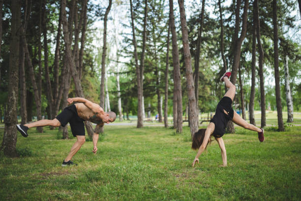 Young couple training in public park Young man and woman doing acrobatics in a park handspring stock pictures, royalty-free photos & images