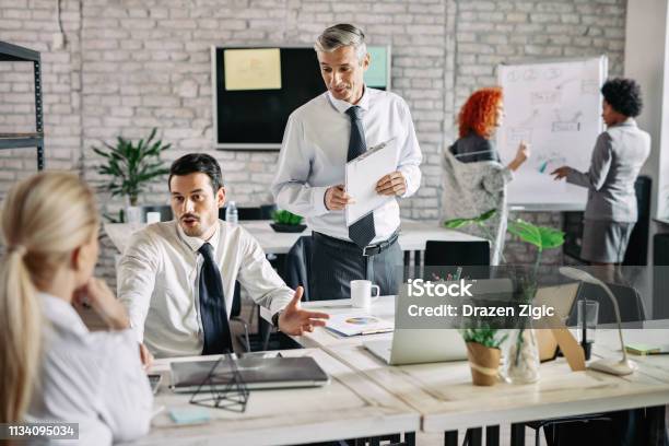Group Of Happy Business People Communicating In The Office Stock Photo - Download Image Now