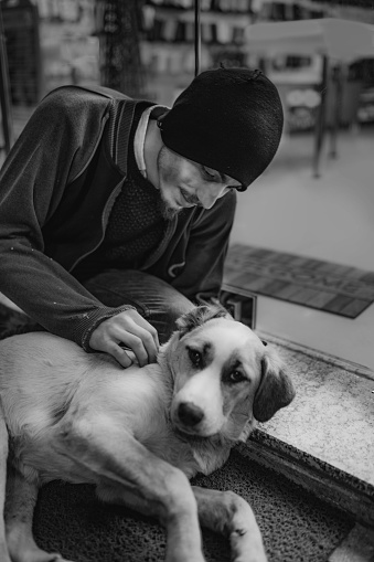 Man beggar loves dog in front of store