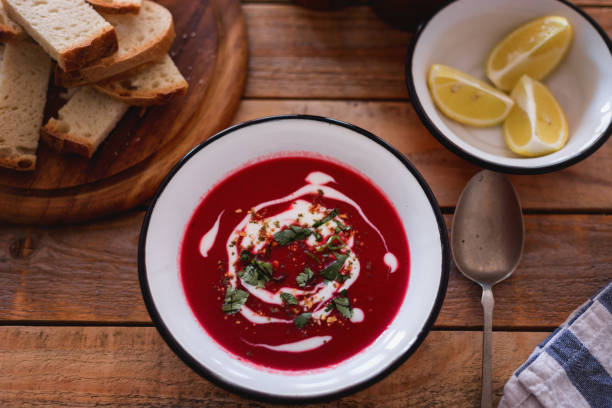Fresh made beetroot soup with bread slices and lemon served in plate, close-up