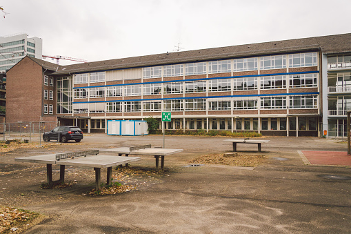 25 October 2018 Germany, Dusseldorf. Facade of building school, school, view of the sports ground with tables for table tennis ping pong in the fall in cloudy weather.