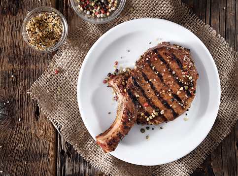 Juicy grilled pork chop with spices on a white plate