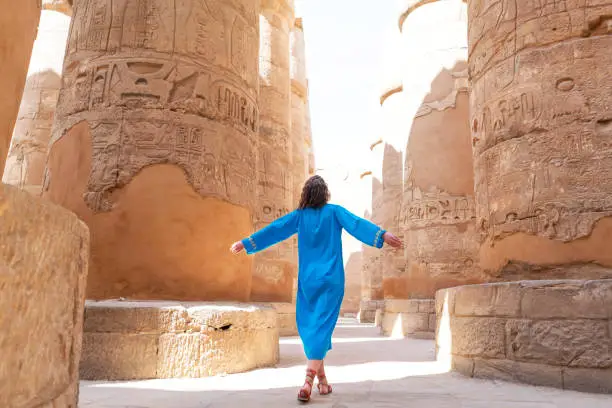 Rear view of a female tourist enjoying a tour at the Great Temple of Amun in Karnak, Egypt.