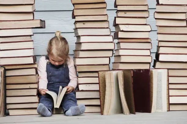 Photo of Young girl sits on stack of books