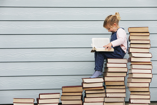 Young girl sits on stack of books