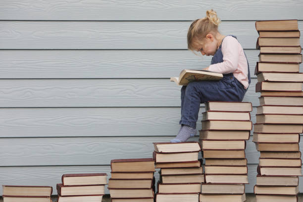 istock Young girl sits on stack of books 1134130519