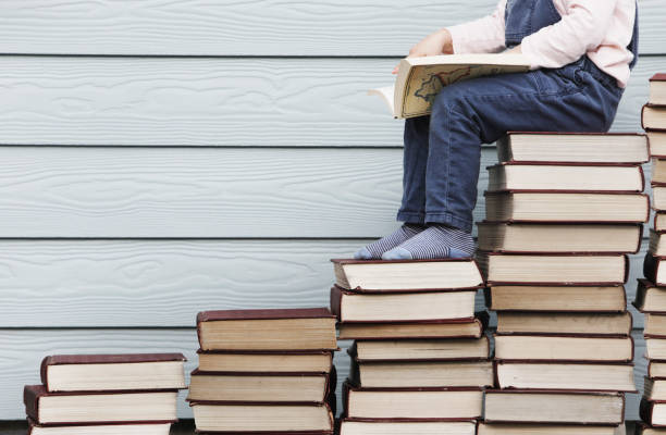 istock Young girl sits on stack of books 1134131037