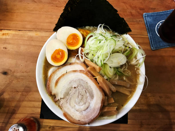 Japanese Ramen with slice pork, Eggs, Seaweed,Spring onion on top in Big White bowl on wooden Table  ; Japanese noodle This menu is popular.