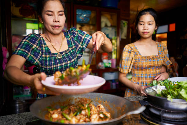 thai mother and daughter plating freshly cooked red curry