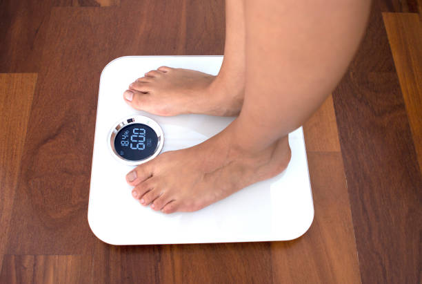istock Woman standing on a digital scale with body fat analyzer 1134138267