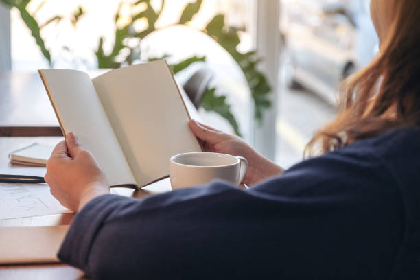 istock a woman holding and opening a blank notebook with coffee cup and papers on the table 1134140634