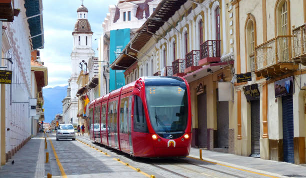 City tram on the street of Cuenca, Ecuador Cuenca, Ecuador - March 4 , 2019: Red city tramway (tram) on Gran Colombia street in historic center of city Cuenca, UNESCO world heritage site, with view of Santo Domingo church at background cuenca ecuador stock pictures, royalty-free photos & images