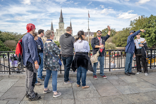 New Orleans, Louisiana / USA - February 14, 2019: A tour guide gives historical information to tourists while overlooking Jackson Square and the St. Louis Cathedral in the famous French Quarter.