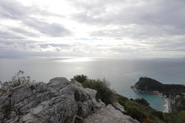 istock View over rocky knoll to sun peaking through clouds along Med coastline 1134149721