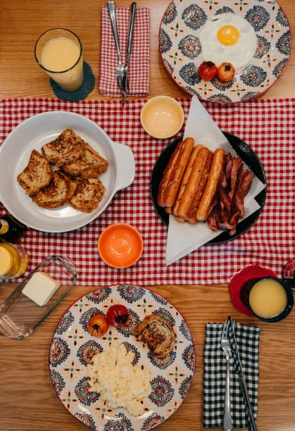 homemade style breakfast with crispy bacon, eggs, french toast, sausage Delicious homemade style breakfast with crispy bacon, eggs, french toast, sausage, grilled tomatoes and orange juice. Top view shot french toast bacon bread butter stock pictures, royalty-free photos & images