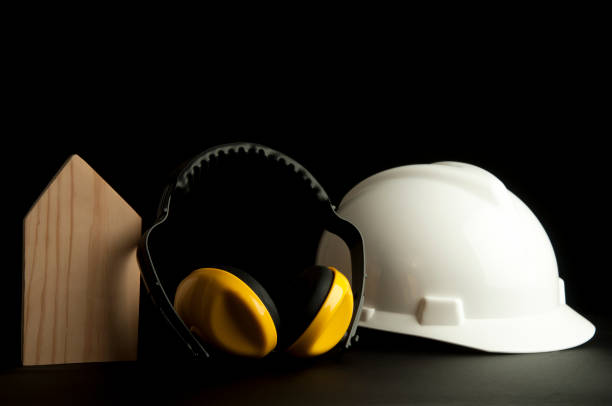 istock Headphone Safety with white hardhat on black background. Home builder safety tools. 1134157881