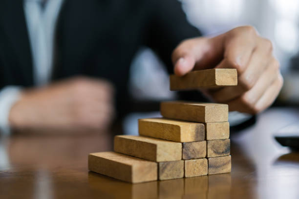 istock Businessman planing and strategy putting wooden blocks risk or success project hands control stack of danger tower challenge game building construction protect at office. 1134161360