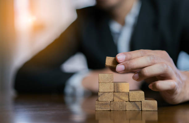 istock Businessman planing and strategy putting wooden blocks risk or success project hands control stack of danger tower challenge game building construction protect at office. 1134161361