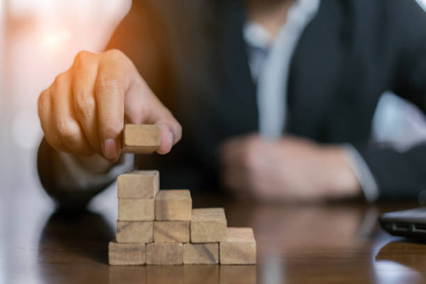 istock Businessman planing and strategy putting wooden blocks risk or success project hands control stack of danger tower challenge game building construction protect at office. 1134161378