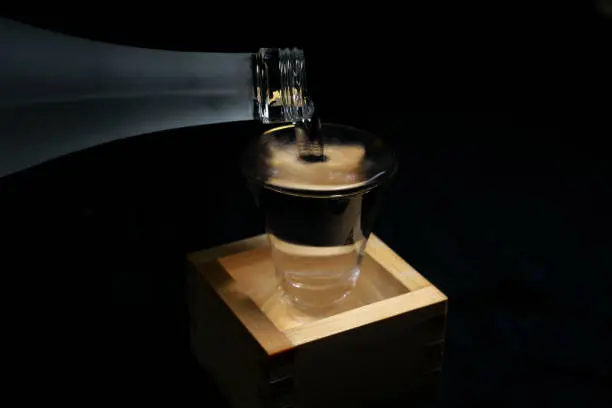 Tokyo,Japan-March 7, 2019: Pouring sake into a glass inside a wooden container for drinking or measuring sake