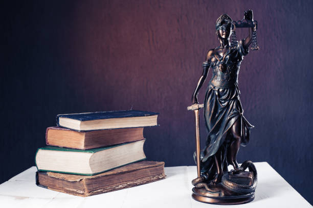 istock Themis figurine stands on a white wooden table next to a stack of old books. 1134167998
