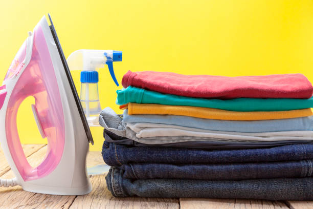 istock iron and stack of colored clothes yellow background 1134168757