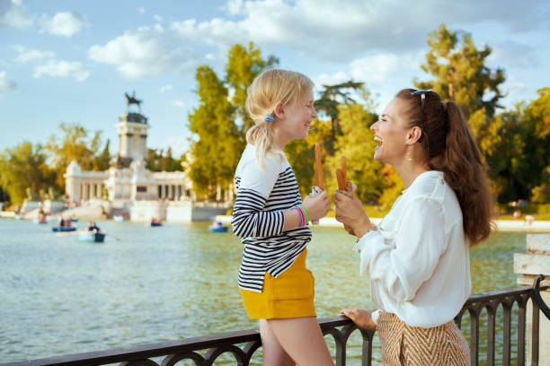 mother and daughter travellers with traditional Spain churro looking at each other stock photo