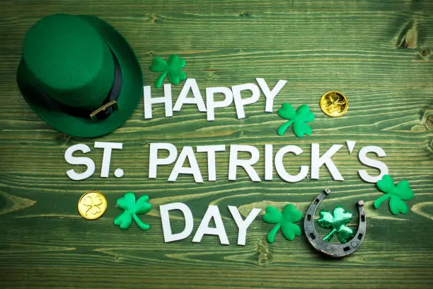 Photo of Happy St Patricks Day letters on green wooden background